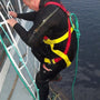 Load image into Gallery viewer, Person in a wetsuit and life jacket climbing a Marcusnet Emergency ladder on a boat.
